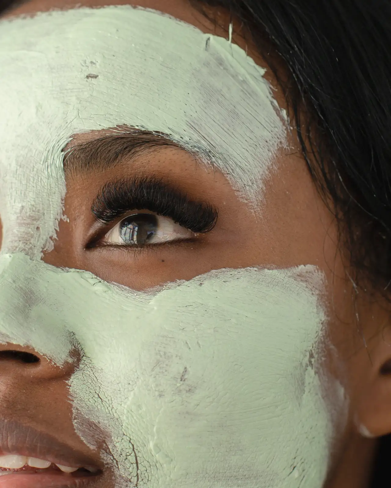 Woman with a green clay mask looking up