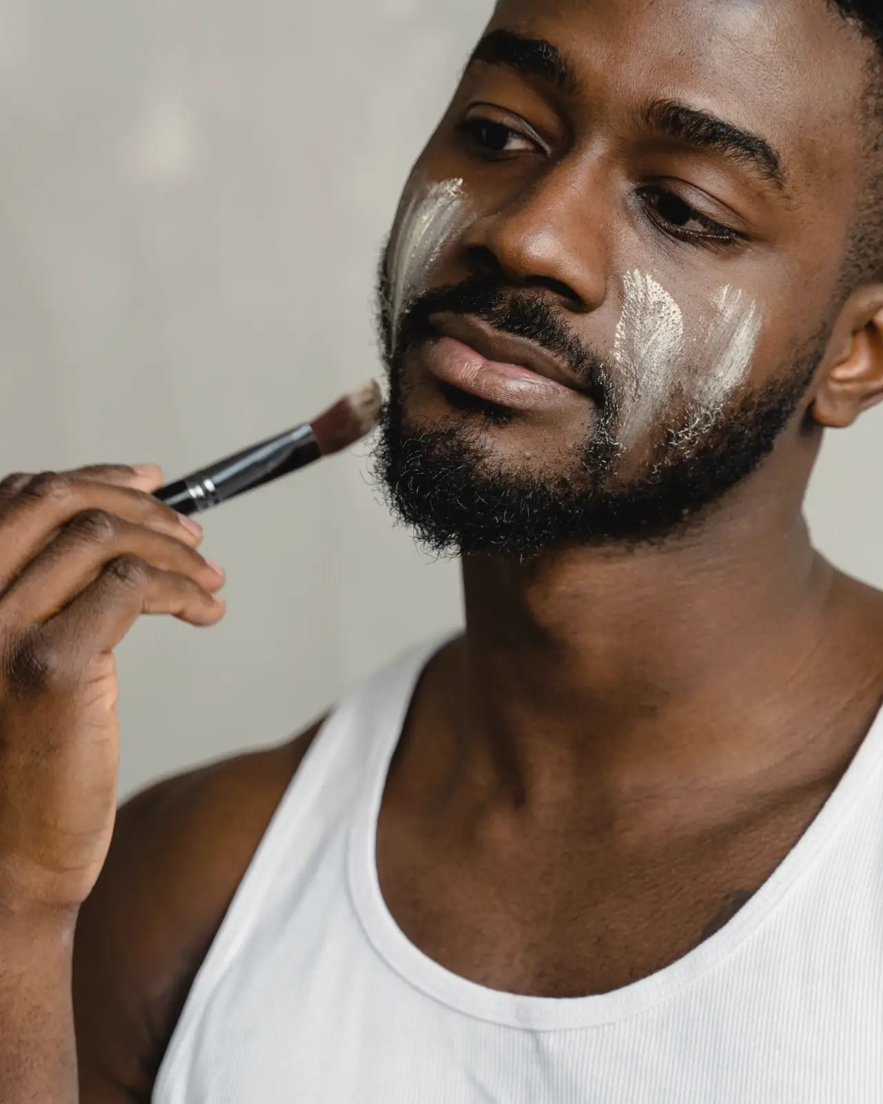 Man applying cream to his face with a small brush