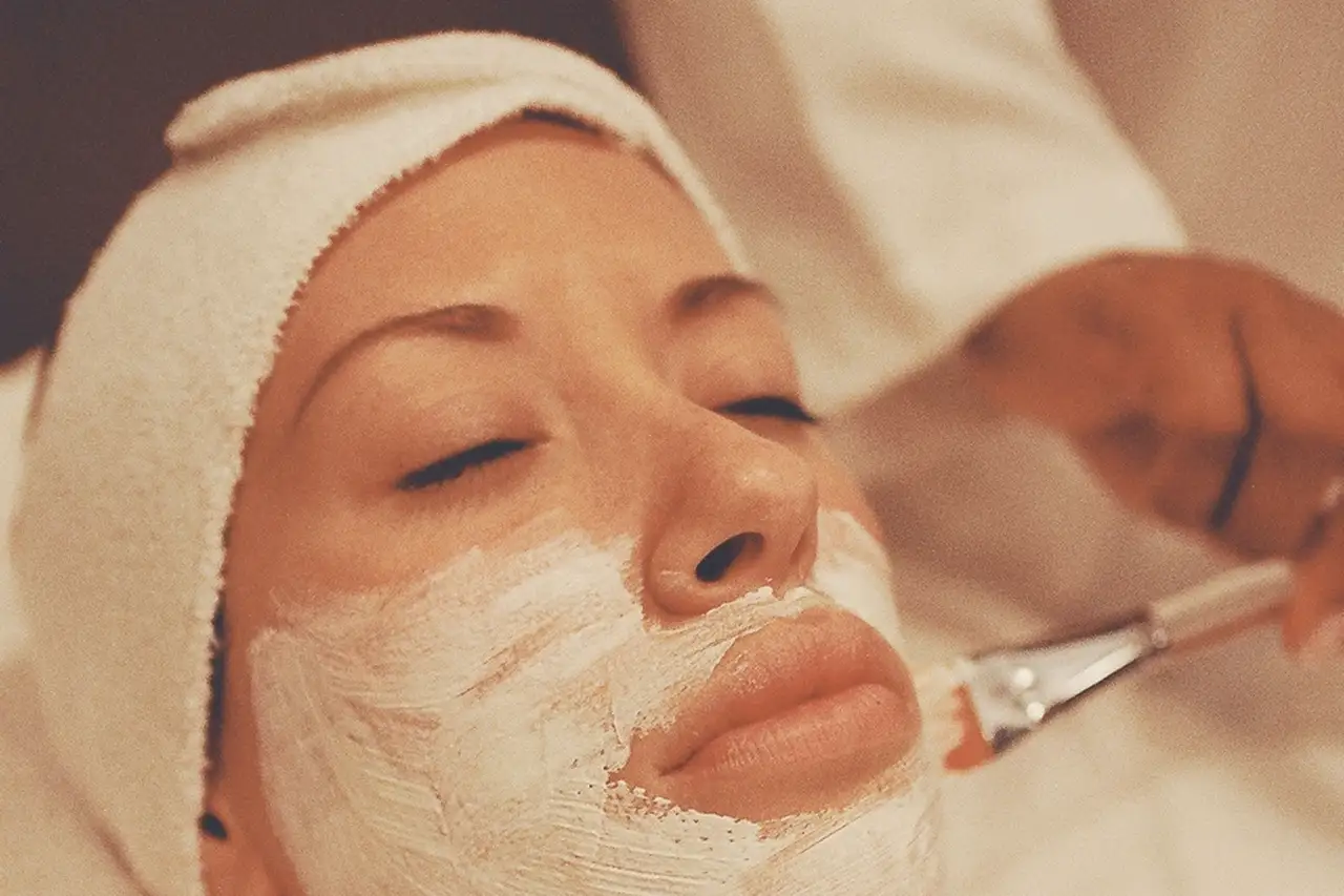 Esthetician applying a treatment mask with a brush to a client's face