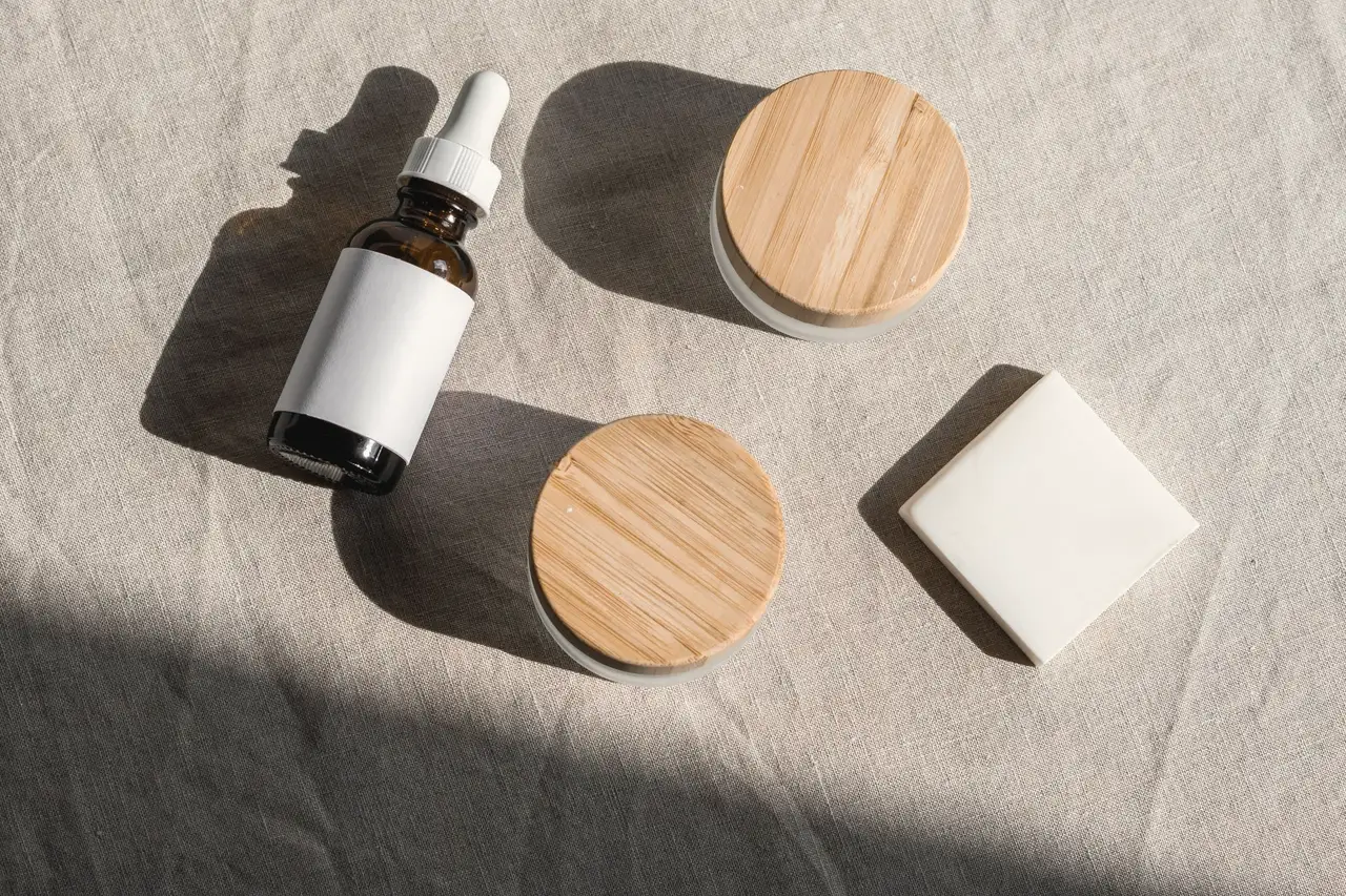 Skincare bottles with wooden lids laid on linen